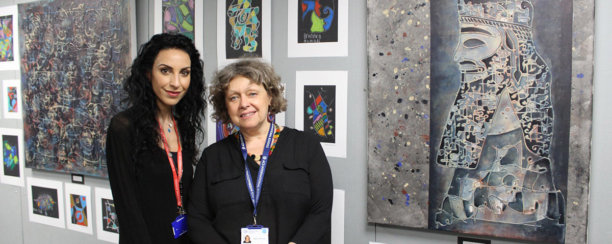 Lina Ogaily and ACS Hillingdon instructor standing in front of Lina's artwork